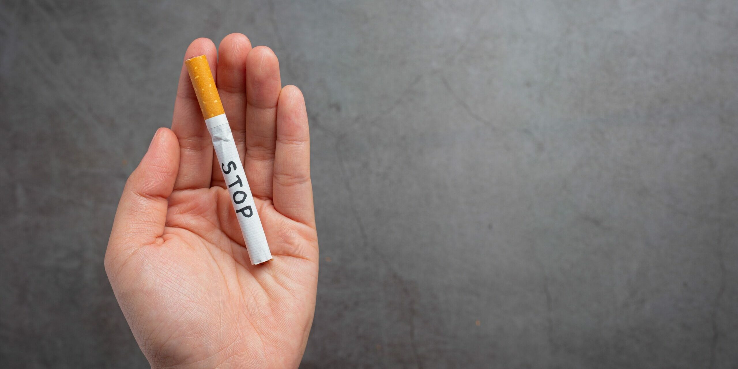 human_hand_holding_cigarette_world_no_tobacco_day_concept_42d77f41a6